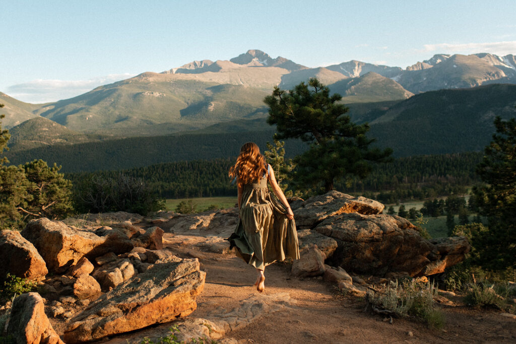 a girl frolics on the rocks overlooking 3M curve in Rocky Mountain National Park