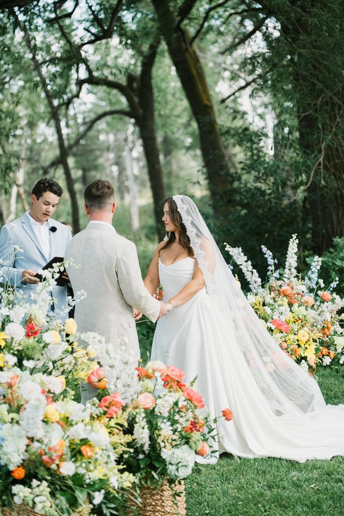 a bride and groom stand in front of guests at their Boulder Flower Farm wedding