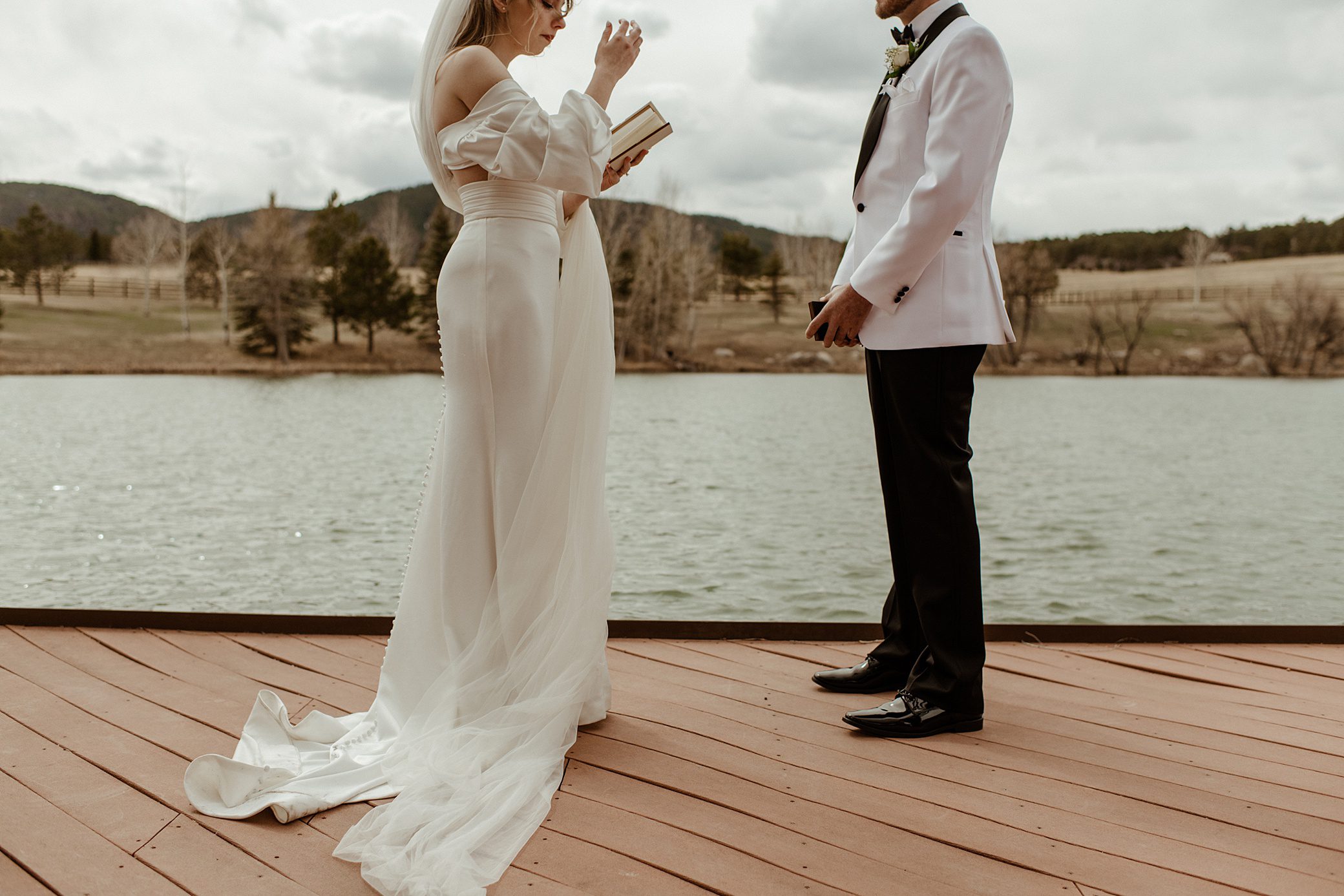 bride and groom reading their vows to each other by the pond of the lower spruce mountain ranch wedding venue