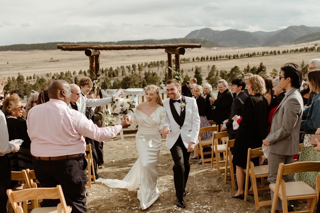 bride and groom walk down the aisle after getting married at Lower Spruce Mountain Ranch's mountainside ceremony location