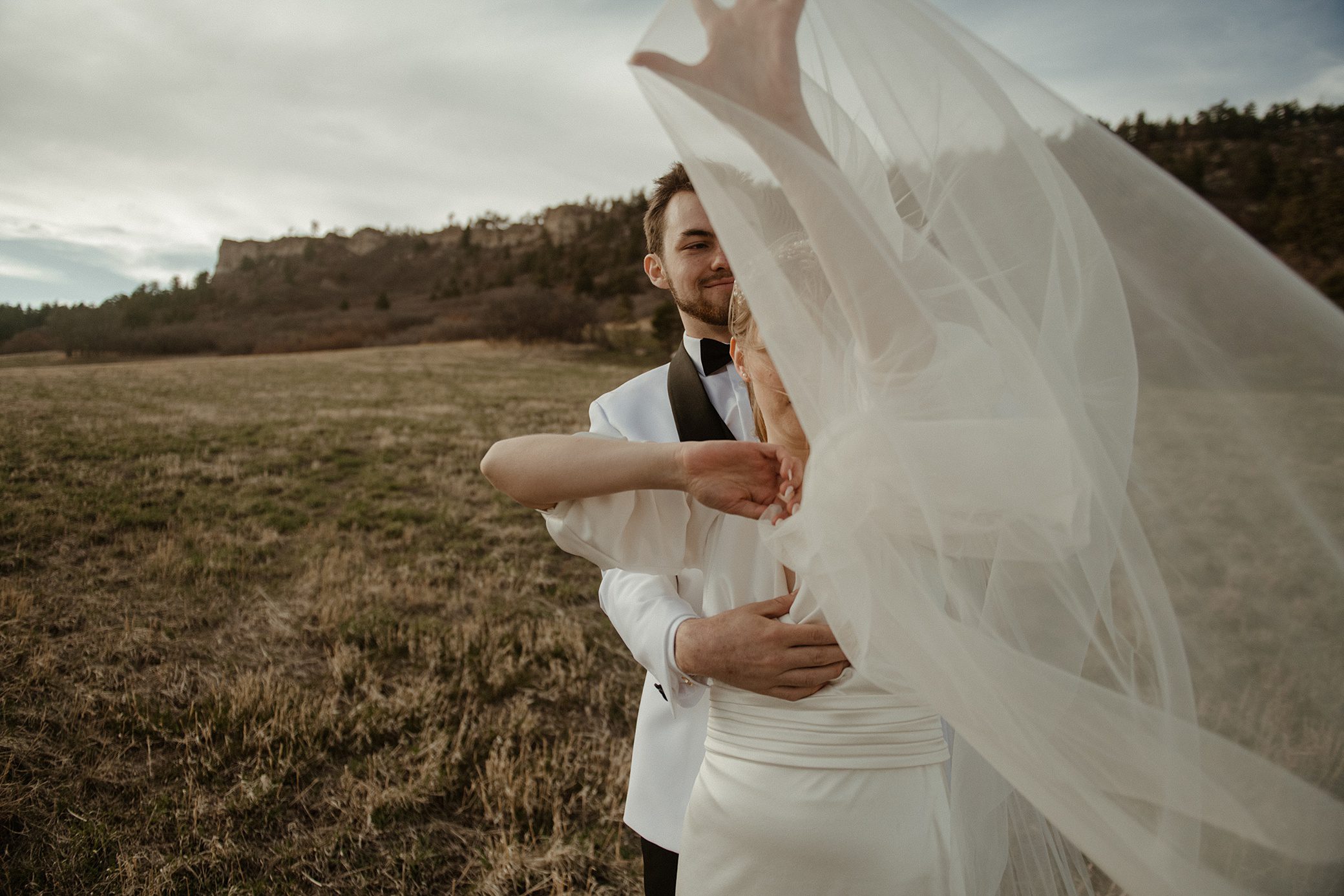a bride tangled in her veil in the fields of Spruce Mountain Ranch wedding venue
