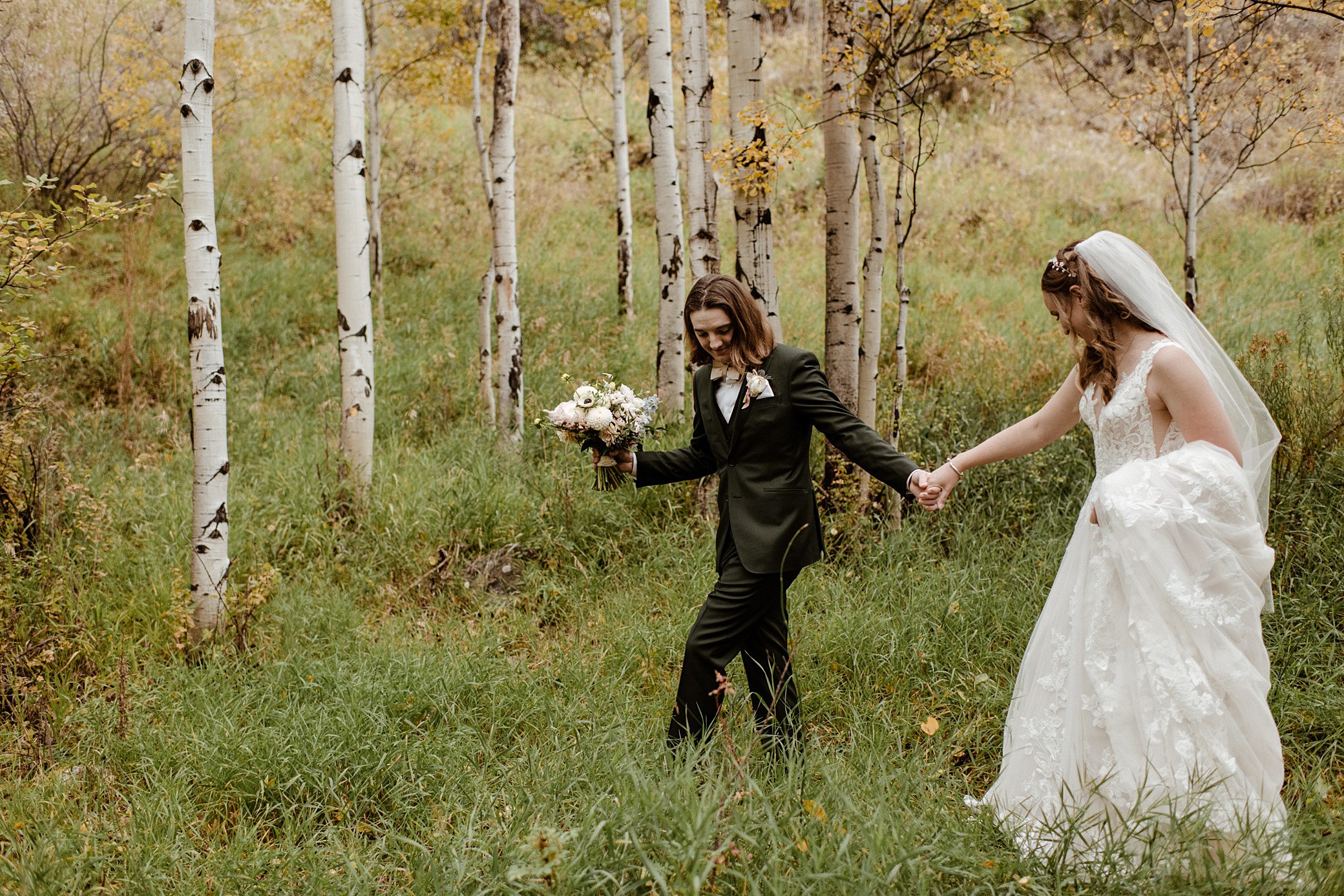 A bride and groom walk through the aspens at the Aspen Meadows Resort Wedding