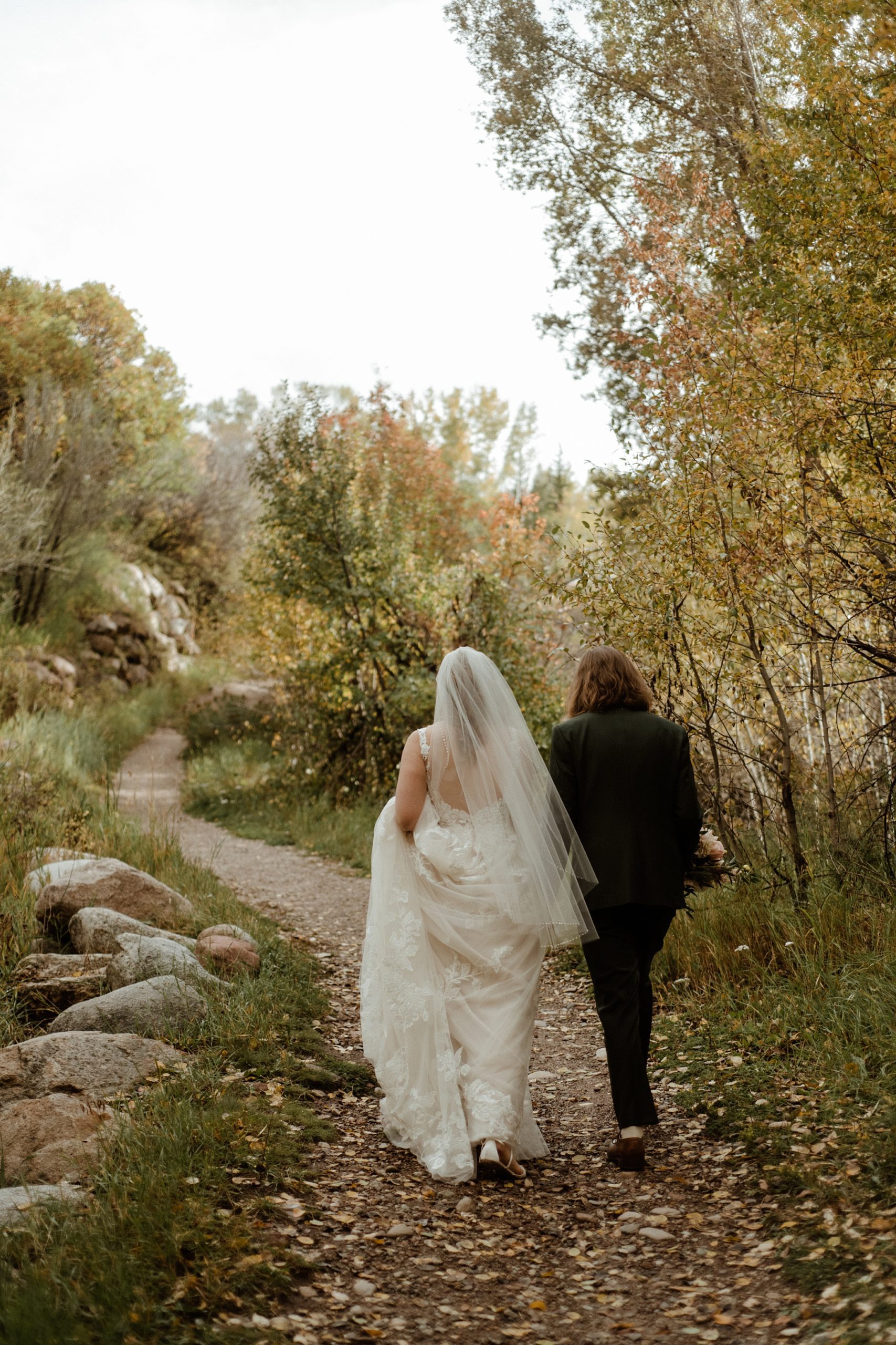 A bride and groom walk around the trails at Aspen Meadows Resort