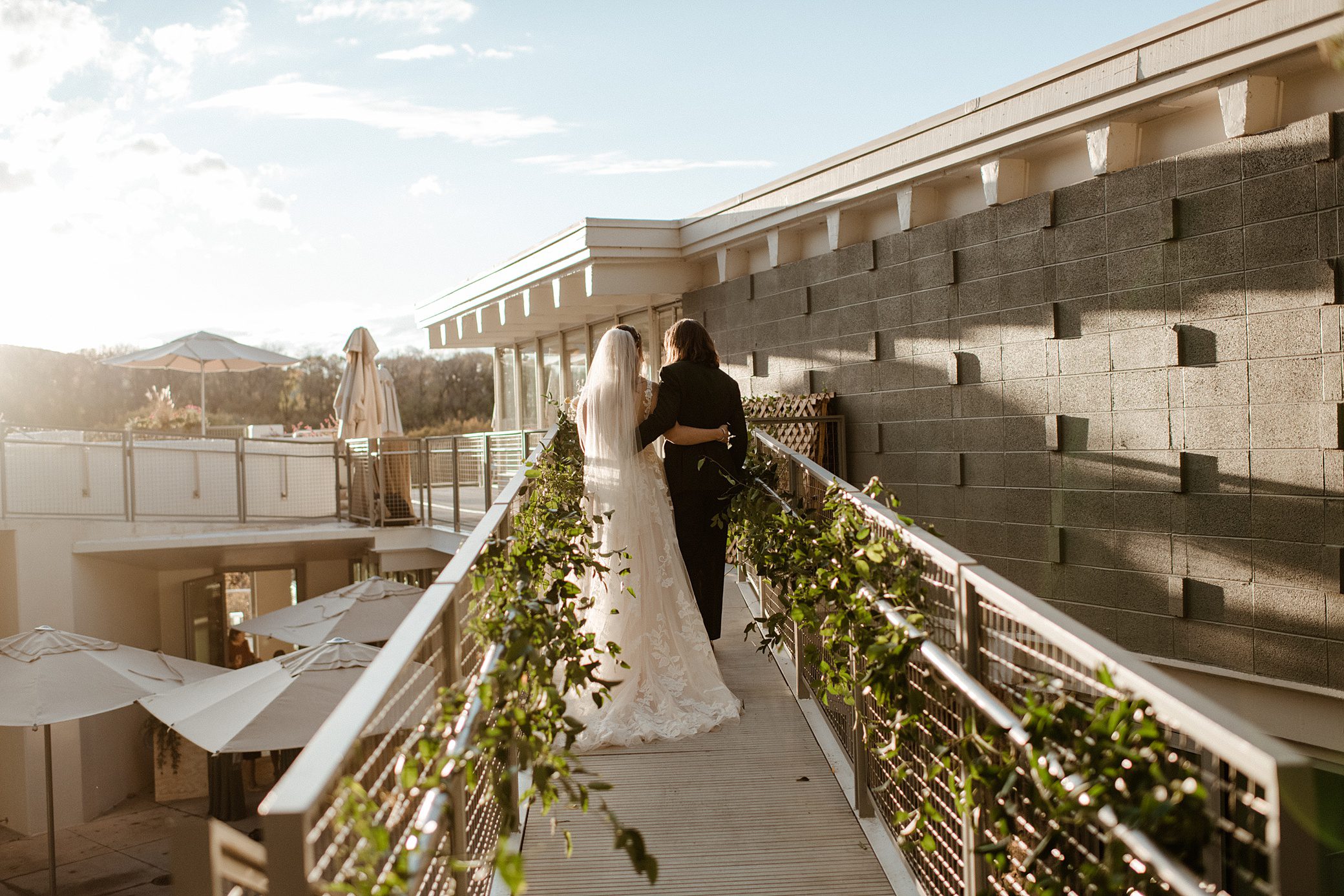 A bride and groom walk down the pathway of the terrace at Aspen Meadows Resort