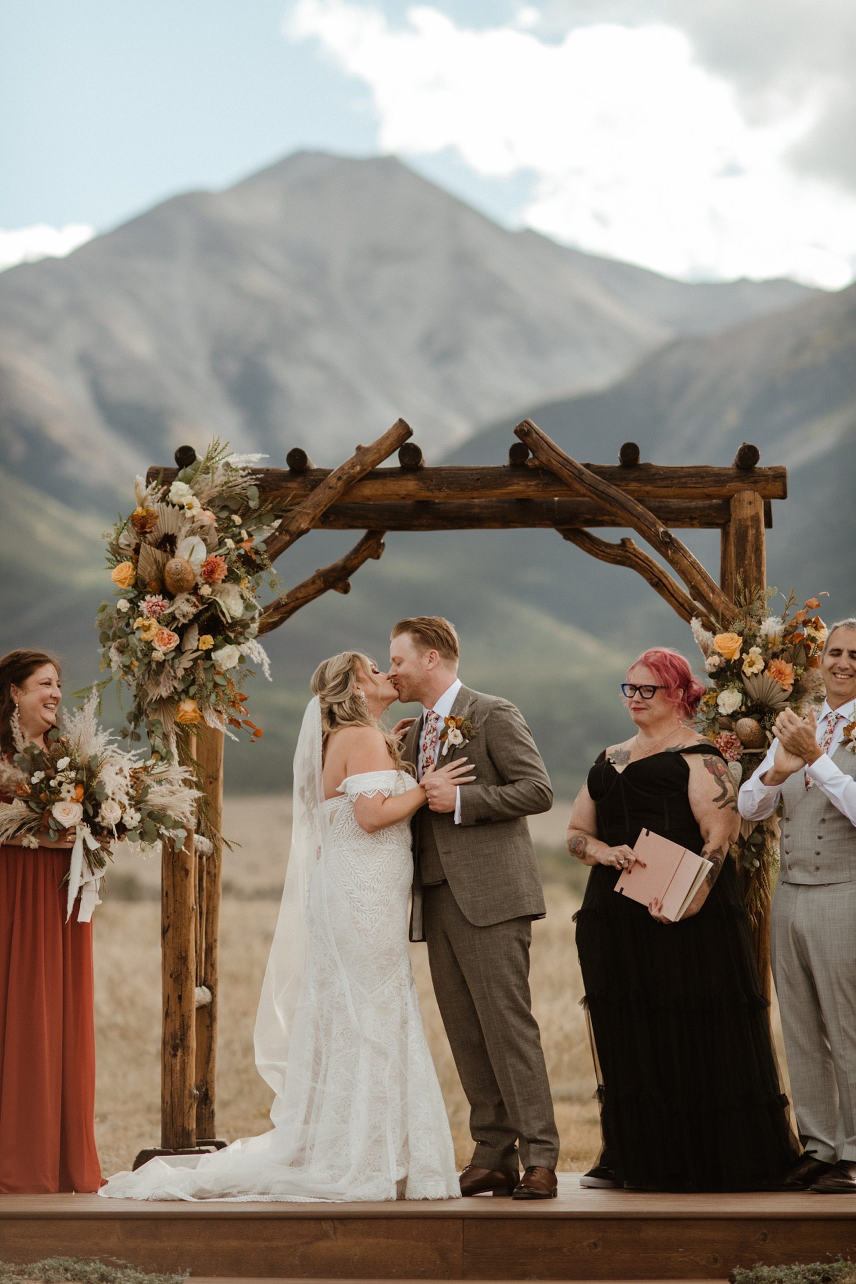a bride and groom kiss under the arch of the ceremony space at The Barn at Sunset Ranch in Buena Vista, CO