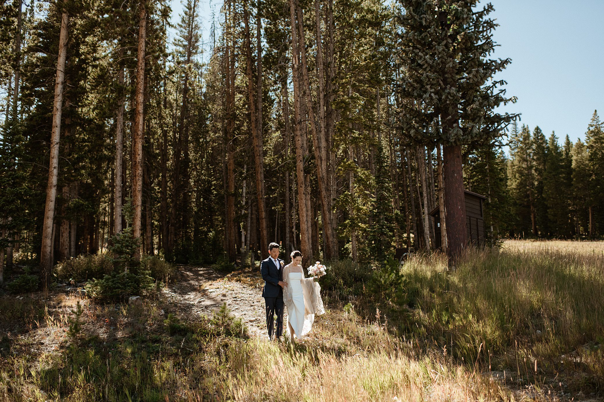 A bride and groom walking out of the woods at Ten Mile Station wedding venue