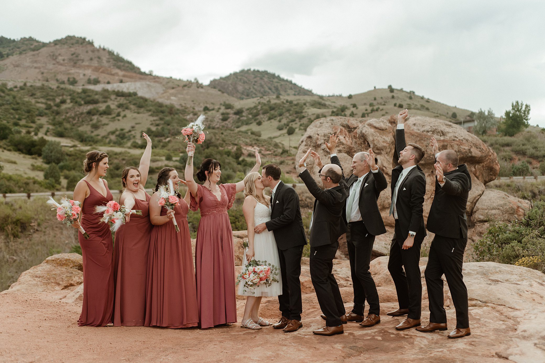 A wedding party celebrates on the red rocks of Willow Ridge Manor wedding venue in Morrison, CO