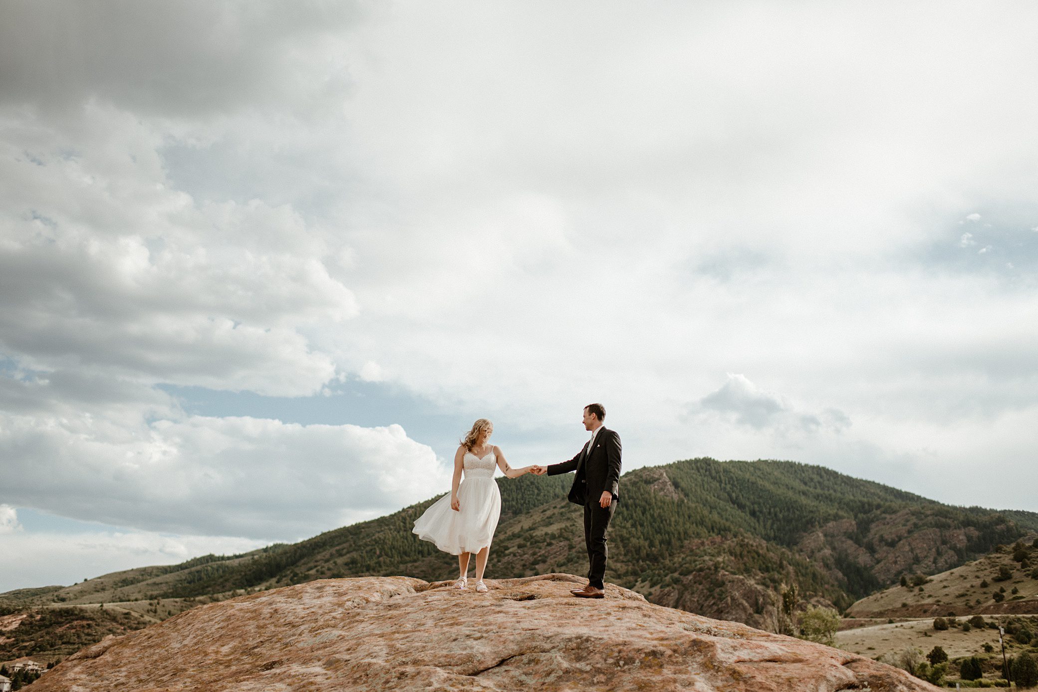 A bride and groom on top of a rock at Willow Ridge Manor wedding venue in Morrison, CO