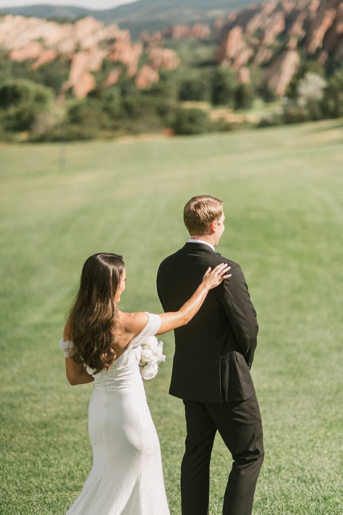 a bride taps her groom on the shoulder for a first look before their Arrowhead Golf Course wedding