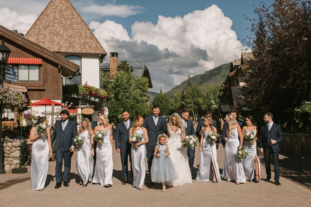 a wedding party walking through the village of vail
