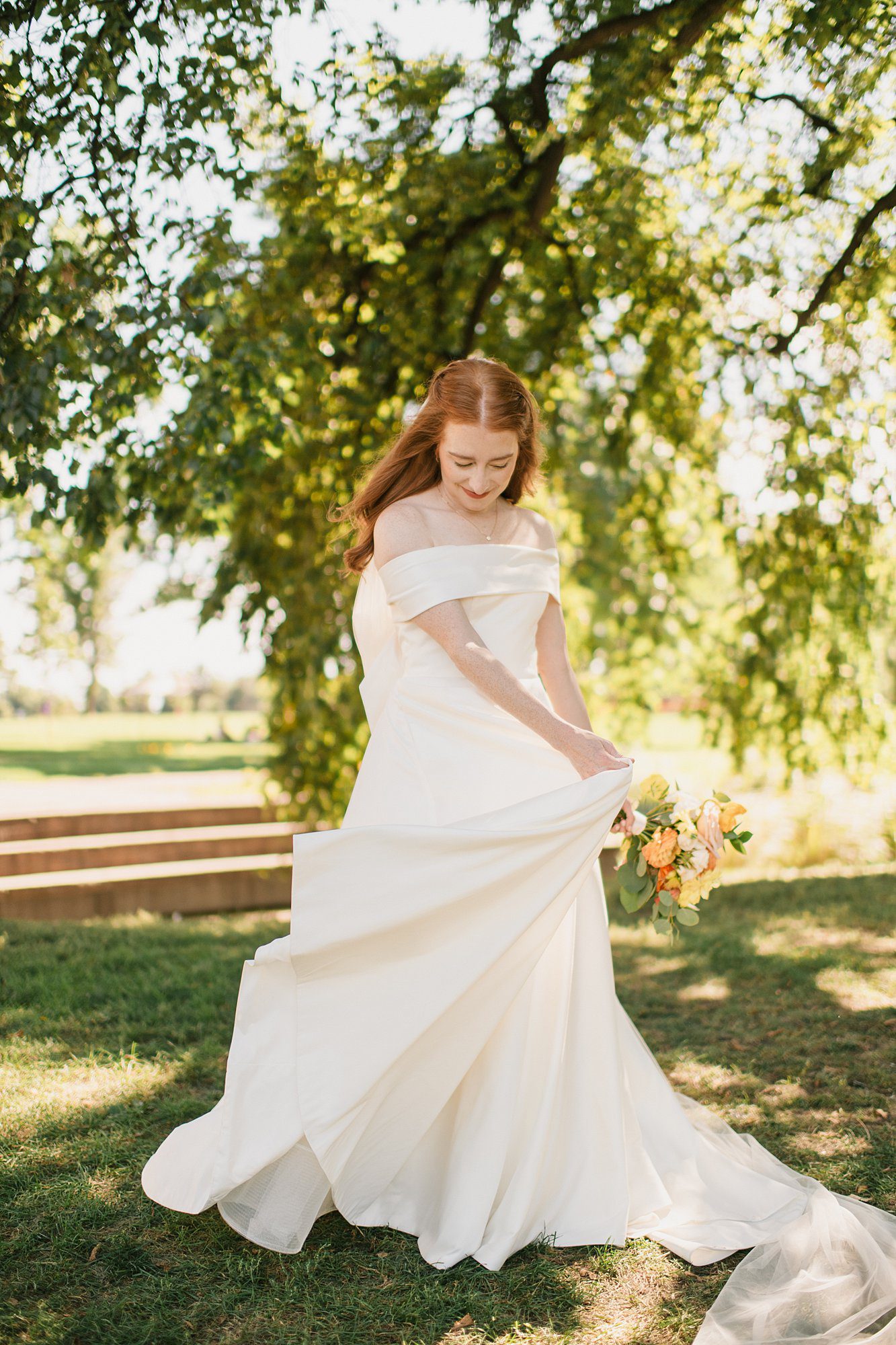 a bride poses in the shade of the trees prior to her Washington Park Boathouse wedding in downtown Denver