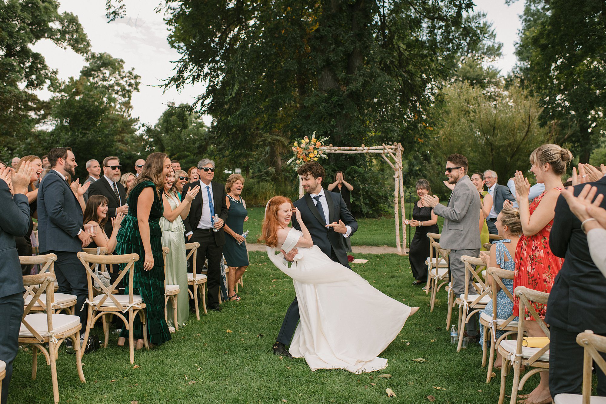 a couple runs down the aisle after their Washington Park Boathouse wedding in downtown Denver