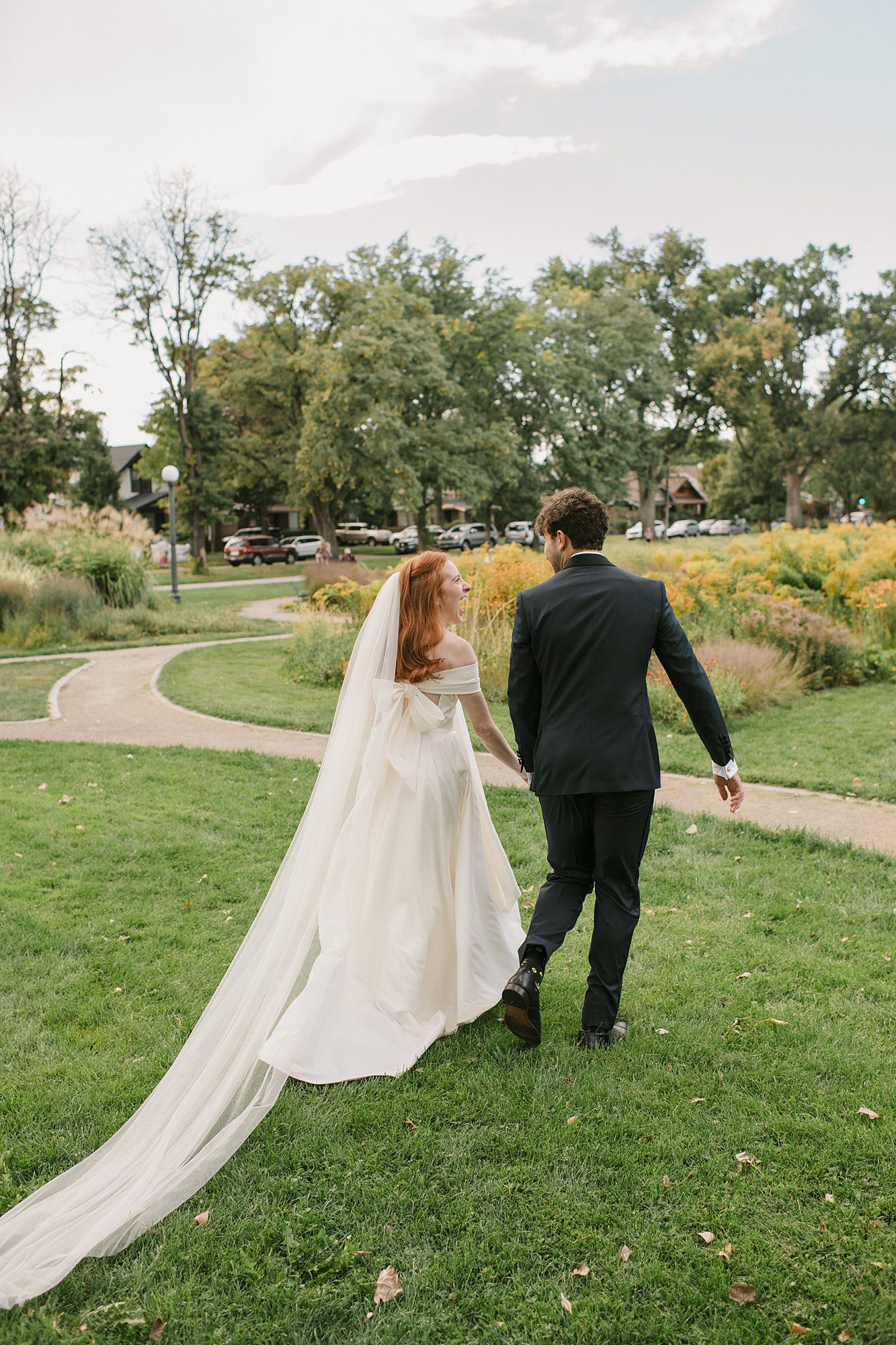 a couple walks through the flowers after their Washington Park Boathouse wedding in downtown Denver