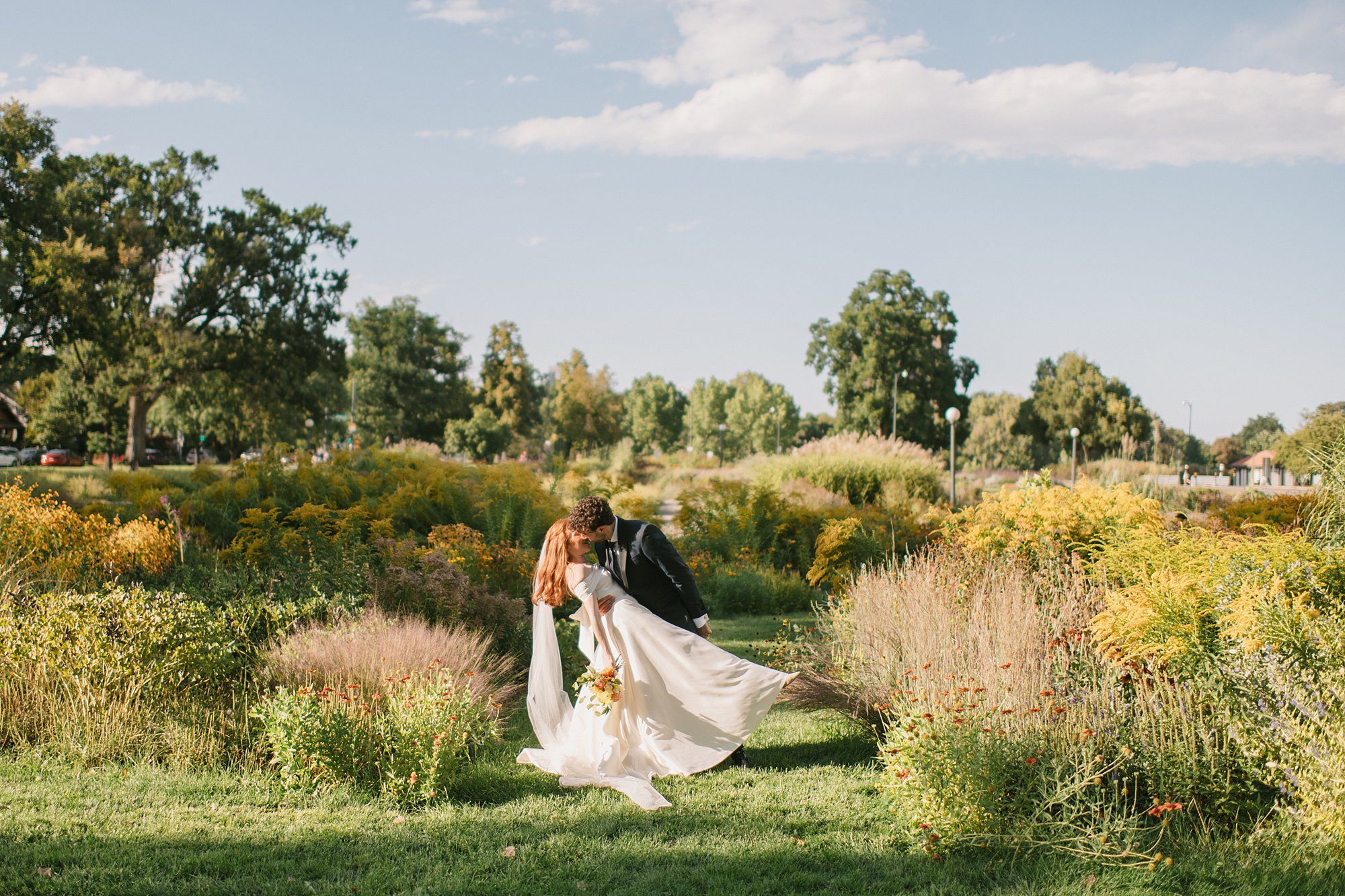 a couple walks through the flowers after their Washington Park Boathouse wedding in downtown Denver