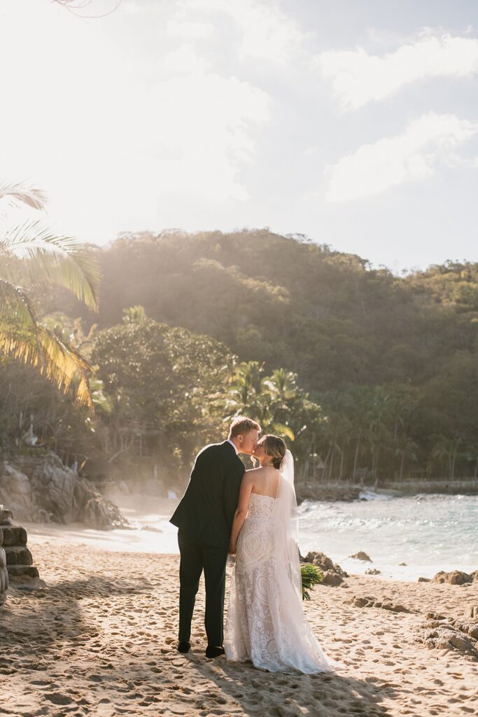 a bride and groom walk on the beach of their private island mexico wedding venue
