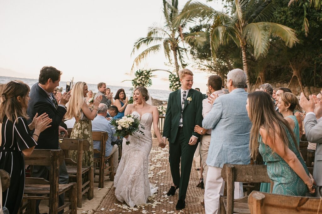 a bride and groom walk down the aisle at their private island mexico wedding venue