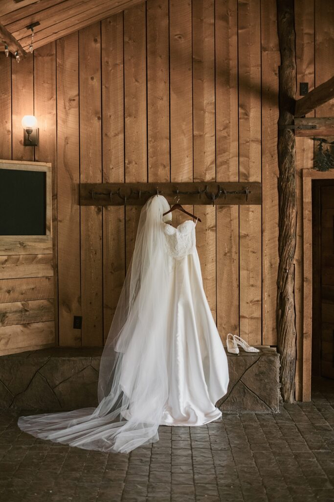 A bride's wedding dress hangs in the barn before a Lower Spruce Mountain Ranch wedding