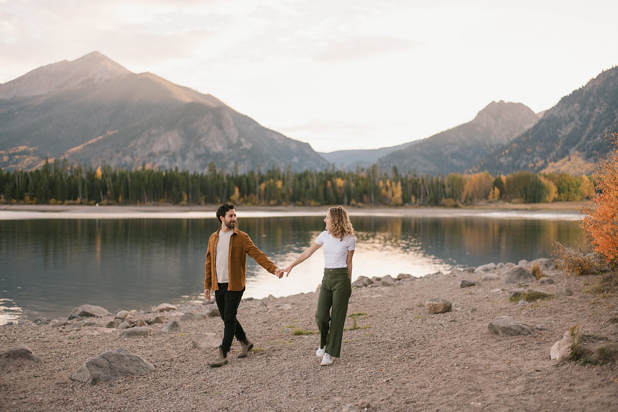 A boy and girl walk the shores of Lake Dillon Reservoir in the fall with peak foliage colors