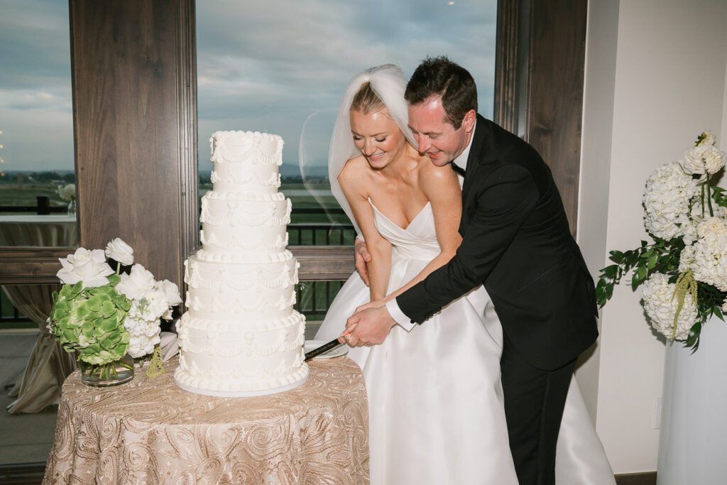 a bride and groom cut their cake at their TPC Colorado wedding
